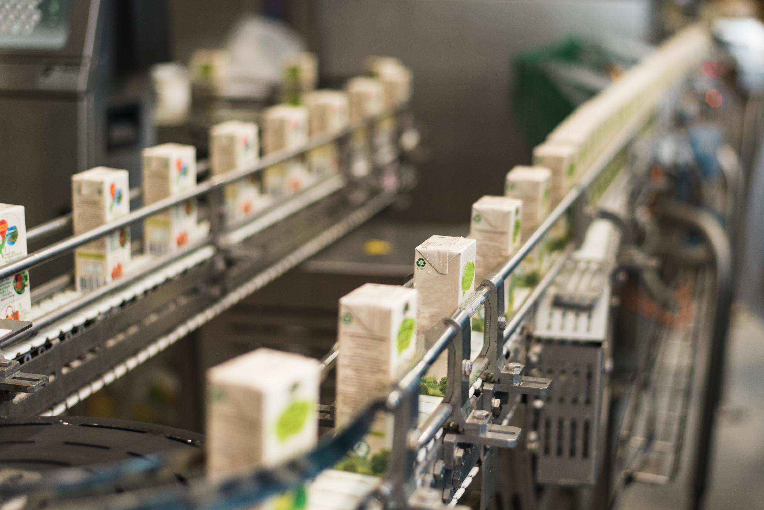 conveyor plant production bottling juices cardboard packaging scaled - Sustainability Strategies in F&B Industry